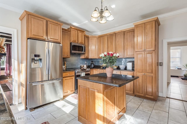 kitchen with appliances with stainless steel finishes, dark stone counters, decorative light fixtures, a notable chandelier, and a center island