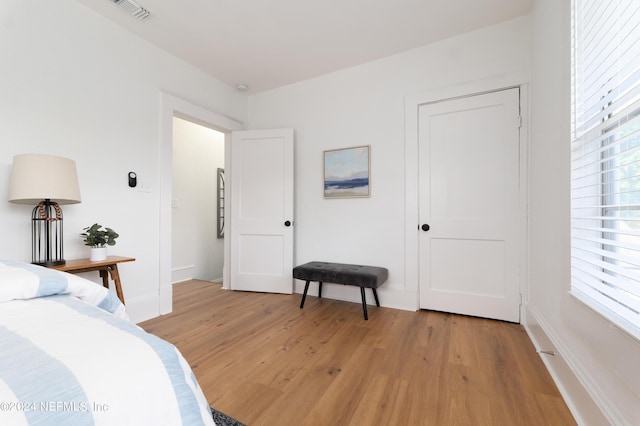 bedroom featuring light wood finished floors, baseboards, multiple windows, and visible vents