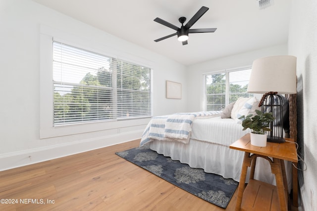 bedroom with baseboards, visible vents, ceiling fan, and wood finished floors