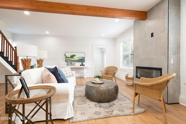 living room with a tile fireplace, recessed lighting, wood finished floors, stairway, and beamed ceiling