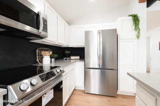 kitchen featuring lofted ceiling, stainless steel appliances, white cabinets, light countertops, and light wood-type flooring