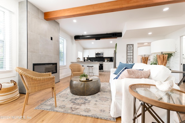 living room with beamed ceiling, a tile fireplace, light wood-style flooring, and recessed lighting