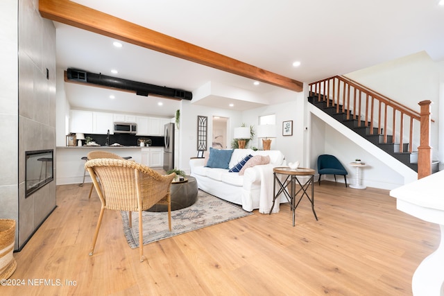 living area with light wood finished floors, stairs, a fireplace, beam ceiling, and recessed lighting