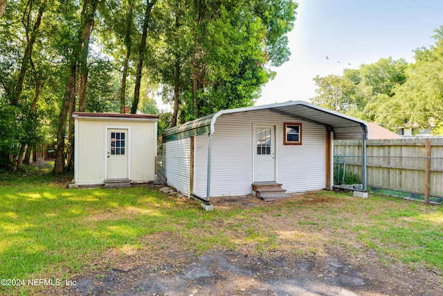 view of outbuilding with entry steps, an outbuilding, fence, and a detached carport