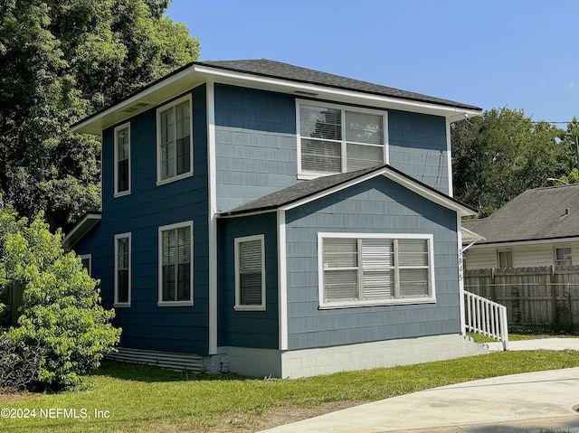 view of side of home featuring a shingled roof and fence