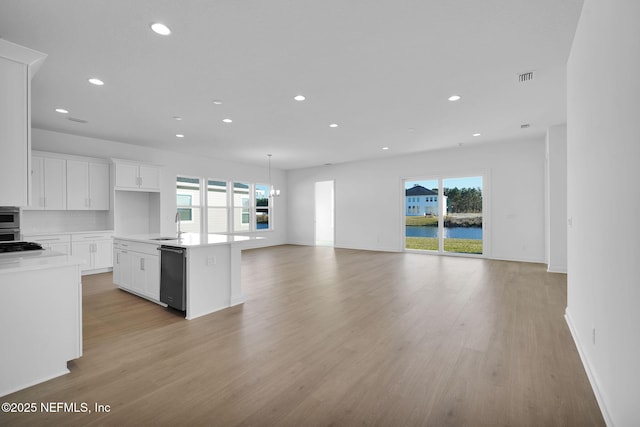 kitchen featuring white cabinets, dishwasher, an island with sink, and plenty of natural light