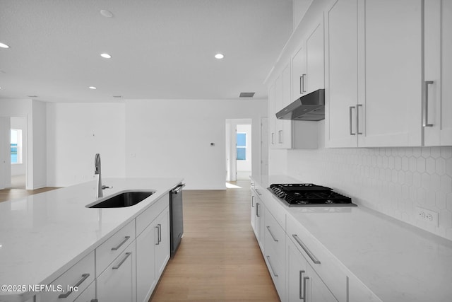 kitchen featuring dishwashing machine, stainless steel gas stovetop, sink, and white cabinetry