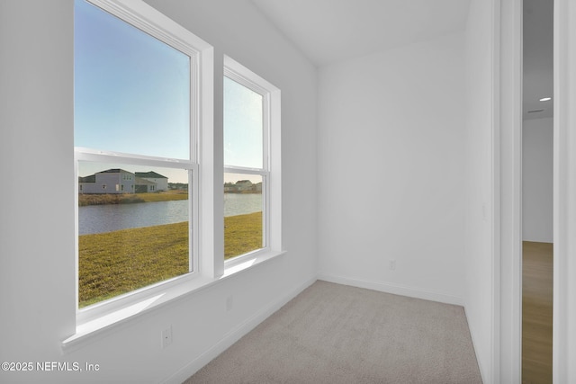 interior space featuring light colored carpet and a water view