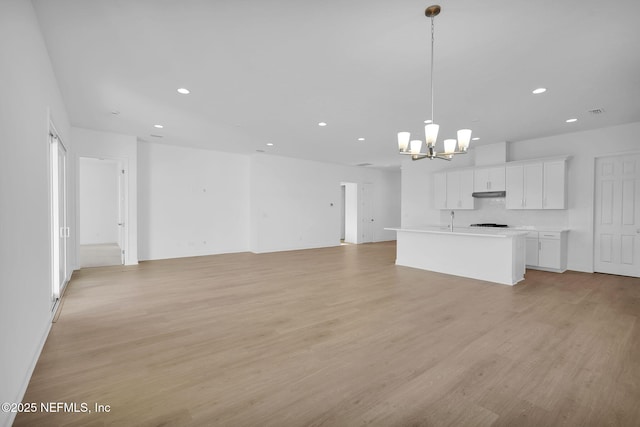 unfurnished living room with light hardwood / wood-style floors, sink, and an inviting chandelier