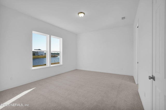 unfurnished room featuring light colored carpet and a water view