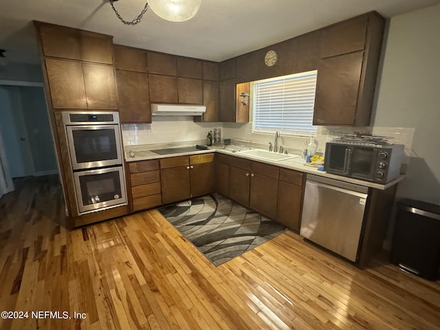 kitchen featuring backsplash, wooden counters, black appliances, sink, and light hardwood / wood-style flooring