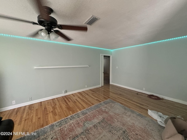 unfurnished living room featuring hardwood / wood-style floors, ceiling fan, and a textured ceiling