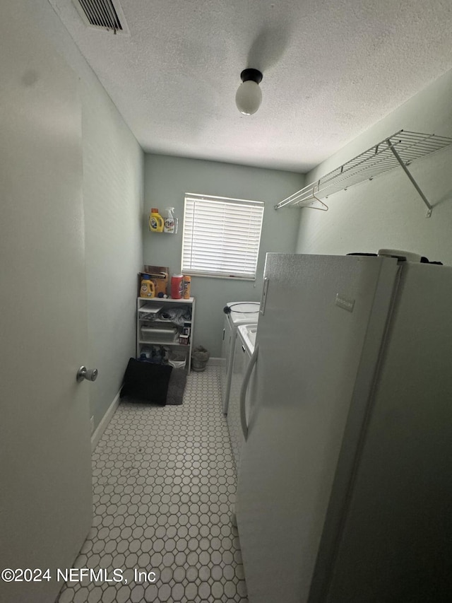 clothes washing area with washing machine and dryer and a textured ceiling