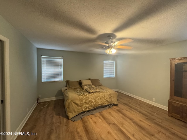 bedroom featuring a textured ceiling, ceiling fan, and dark wood-type flooring