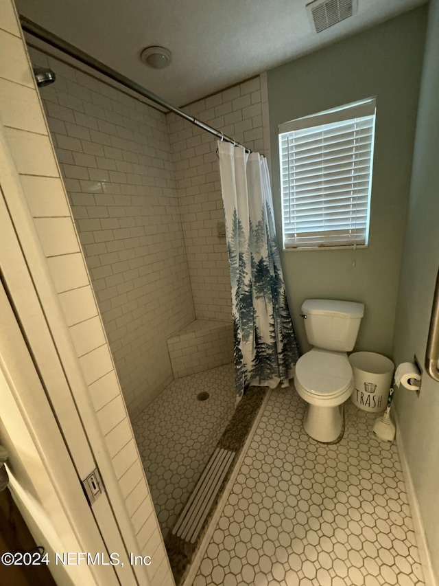 bathroom with a shower with shower curtain, tile patterned flooring, and toilet