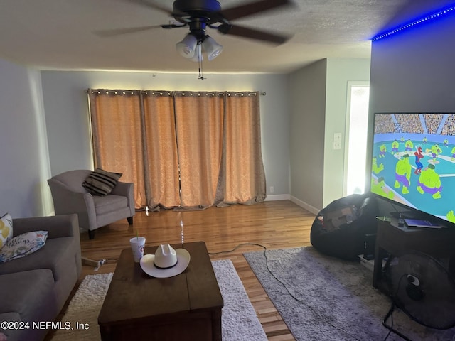 living room featuring ceiling fan, wood-type flooring, and a textured ceiling