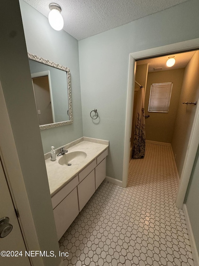 bathroom with tile patterned floors, a shower with curtain, vanity, and a textured ceiling