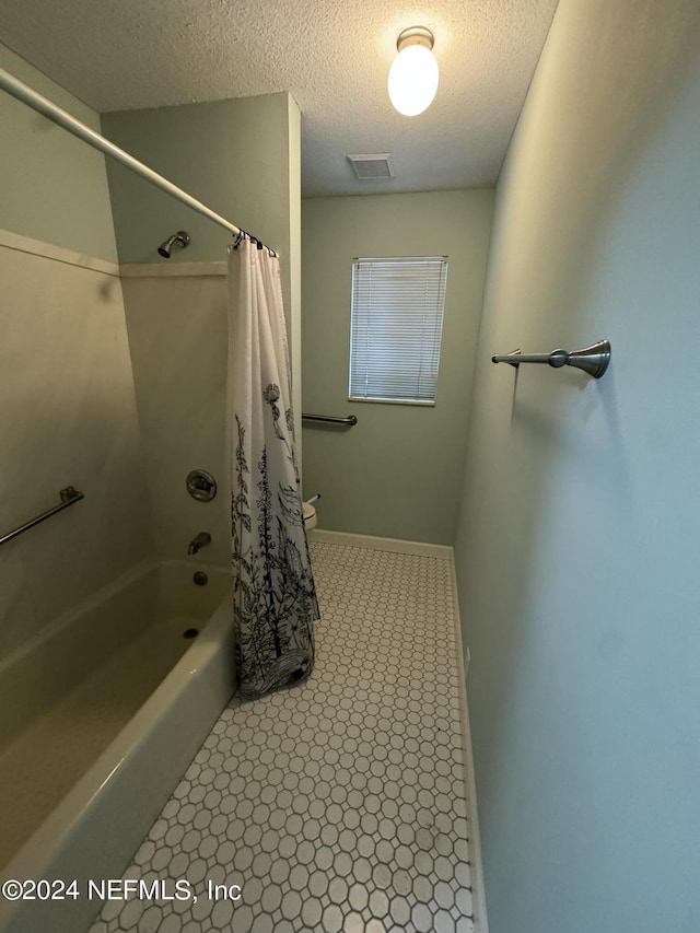 bathroom with a textured ceiling and shower / bath combo with shower curtain