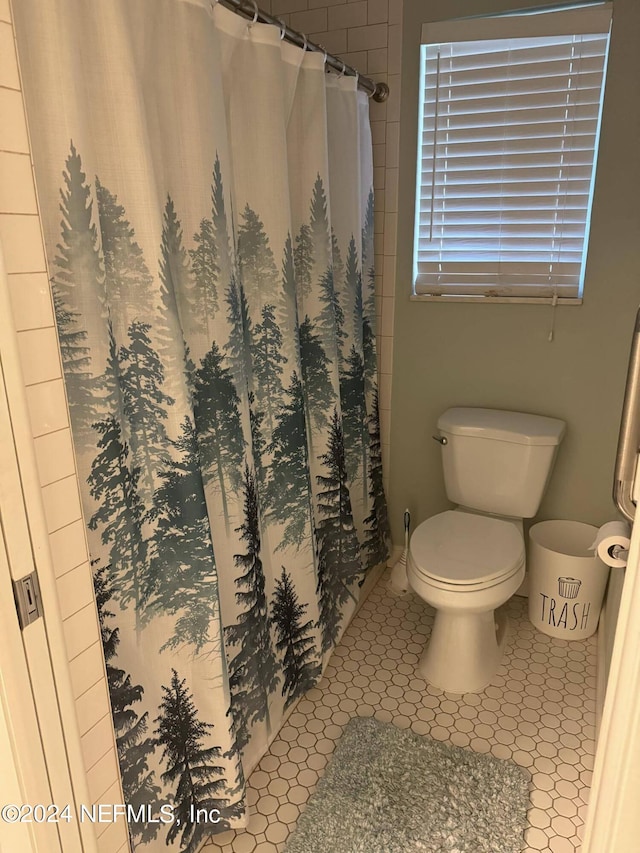 bathroom featuring a shower with curtain, toilet, and tile patterned floors