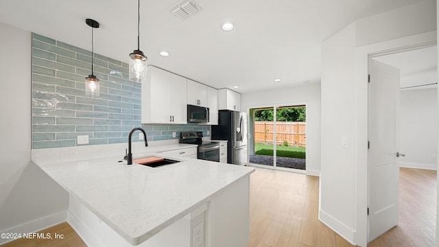 kitchen featuring hanging light fixtures, decorative backsplash, sink, appliances with stainless steel finishes, and kitchen peninsula