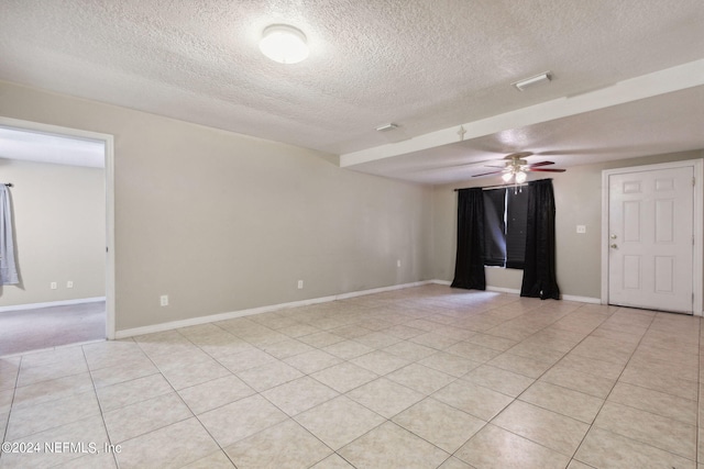 empty room featuring a textured ceiling, ceiling fan, and light tile patterned floors