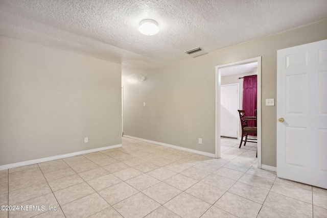 tiled spare room featuring a textured ceiling