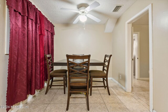 tiled dining area with ceiling fan and a textured ceiling