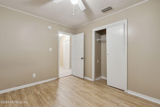 unfurnished bedroom featuring a closet, light hardwood / wood-style floors, ceiling fan, and a textured ceiling