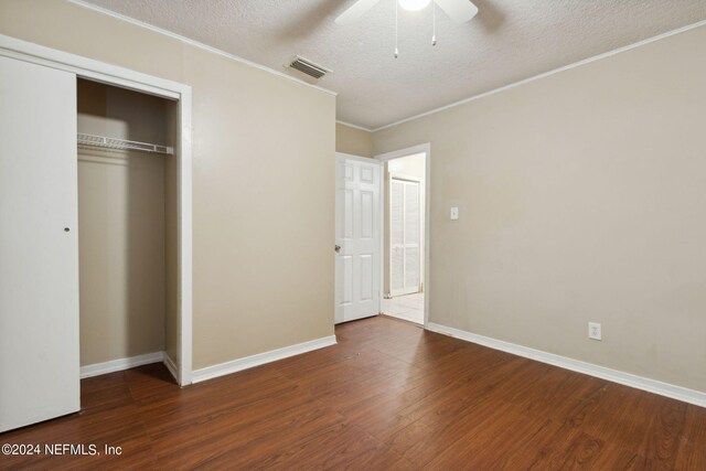 unfurnished bedroom with ceiling fan, ornamental molding, a textured ceiling, a closet, and dark hardwood / wood-style flooring