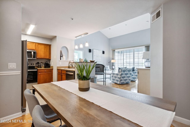 dining room featuring sink, light hardwood / wood-style floors, and lofted ceiling
