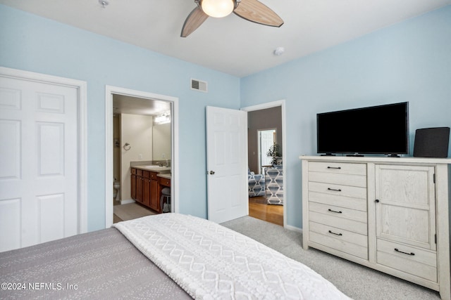carpeted bedroom featuring ensuite bathroom, ceiling fan, and sink