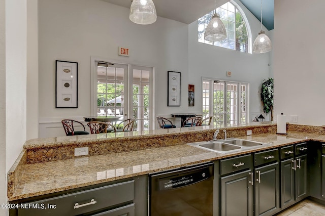 kitchen with dishwasher, sink, light stone counters, a towering ceiling, and pendant lighting