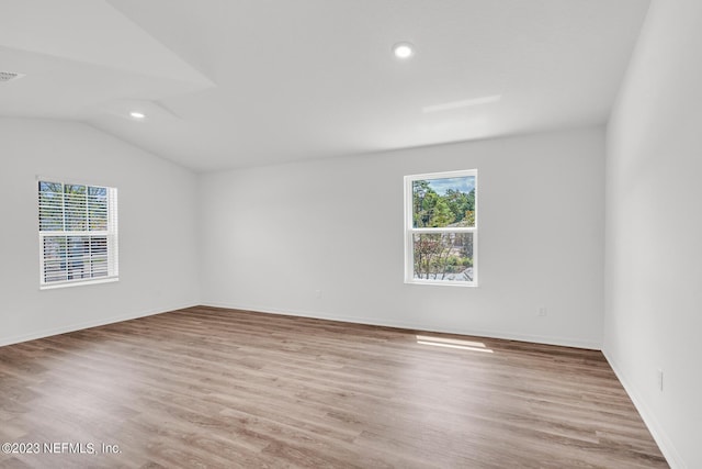 unfurnished room with vaulted ceiling and light wood-type flooring