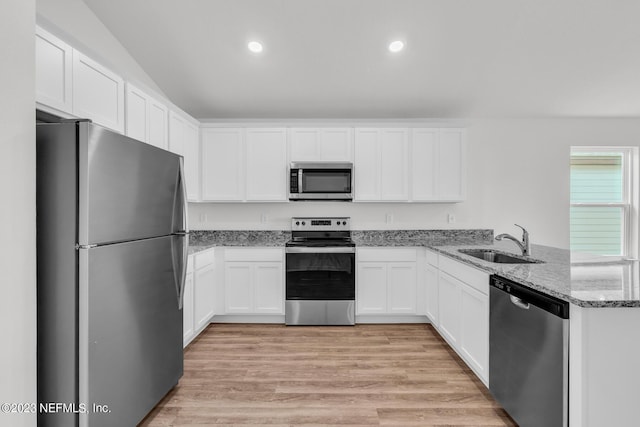 kitchen with kitchen peninsula, stainless steel appliances, sink, dark stone countertops, and white cabinets