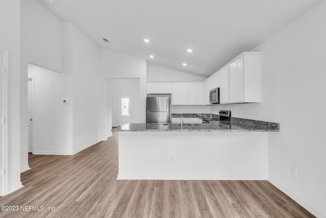 kitchen with kitchen peninsula, appliances with stainless steel finishes, white cabinets, and dark stone counters