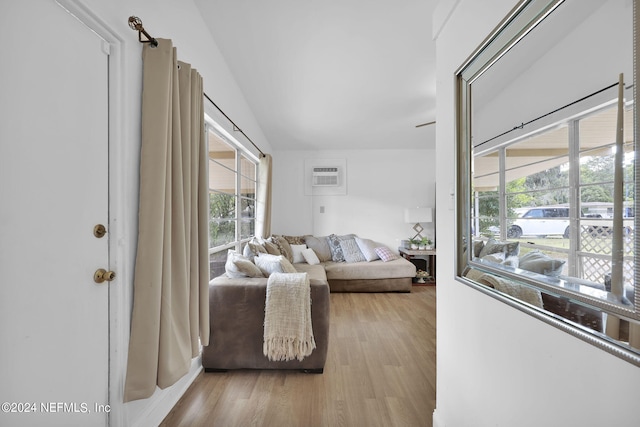 living room featuring a wall mounted air conditioner, light hardwood / wood-style floors, and a healthy amount of sunlight