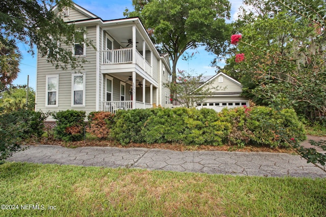 view of front facade featuring ceiling fan, a garage, a front lawn, and a balcony