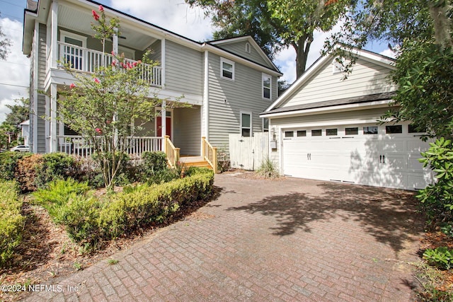 front of property featuring a garage, a balcony, and covered porch