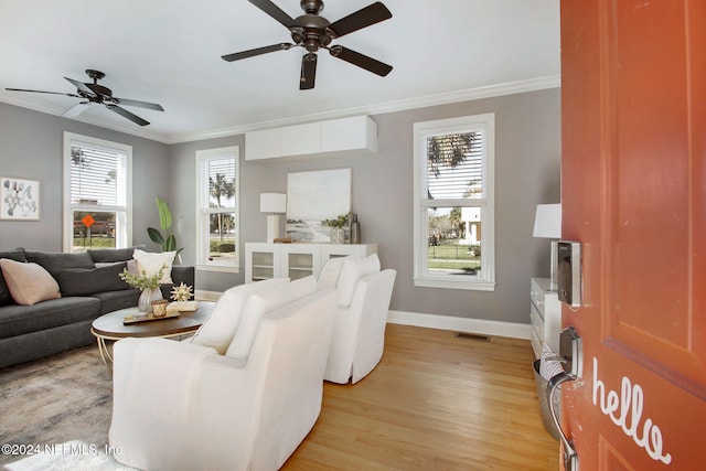 living room featuring crown molding, a wealth of natural light, ceiling fan, and light wood-type flooring