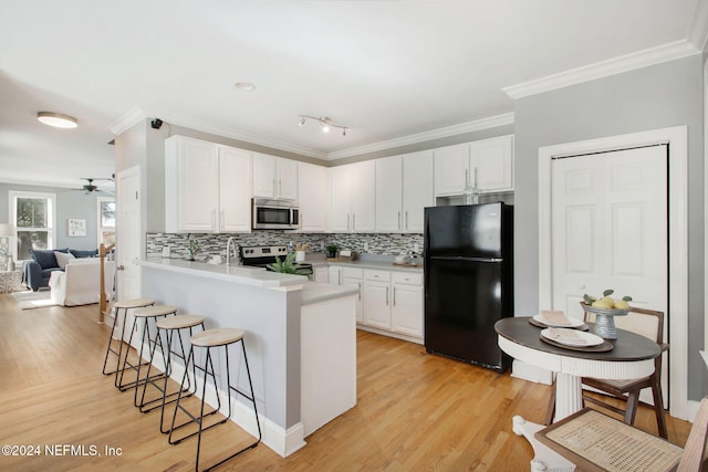 kitchen featuring appliances with stainless steel finishes, a breakfast bar area, white cabinets, and kitchen peninsula