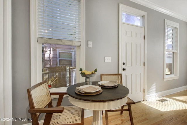 dining area with ornamental molding and light hardwood / wood-style floors