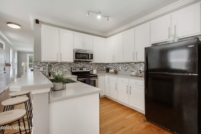 kitchen with appliances with stainless steel finishes, white cabinets, a kitchen bar, kitchen peninsula, and crown molding