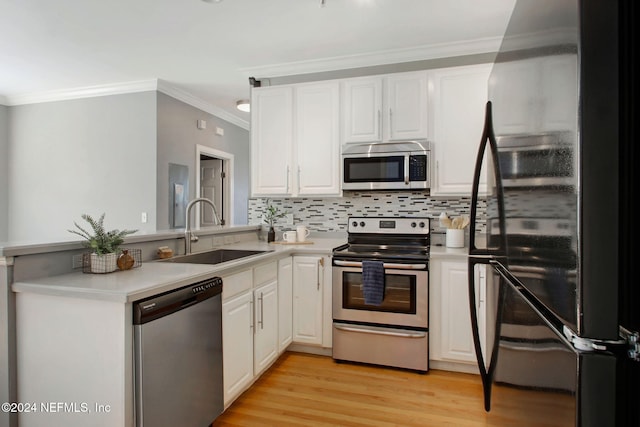 kitchen featuring appliances with stainless steel finishes, sink, white cabinets, decorative backsplash, and light hardwood / wood-style floors