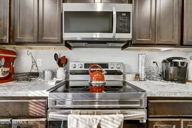 kitchen with dark brown cabinetry and appliances with stainless steel finishes