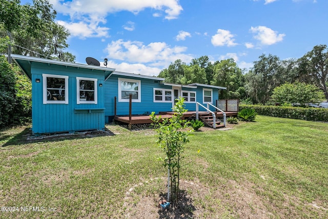 rear view of house with a wooden deck and a lawn