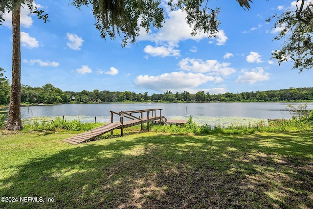 view of dock featuring a lawn and a water view