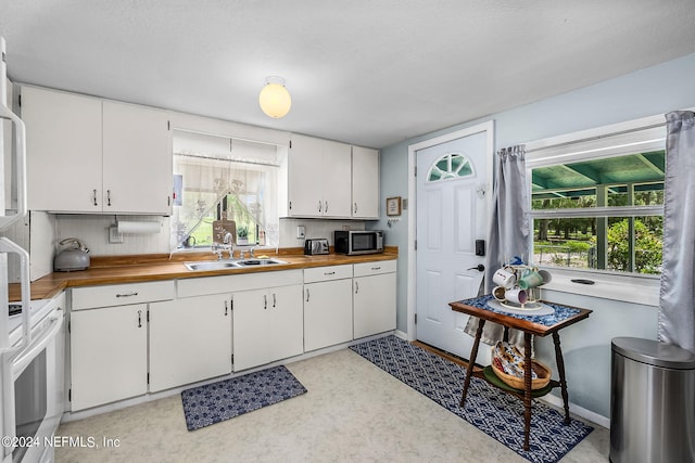 kitchen featuring white cabinetry, sink, white electric range, and butcher block countertops