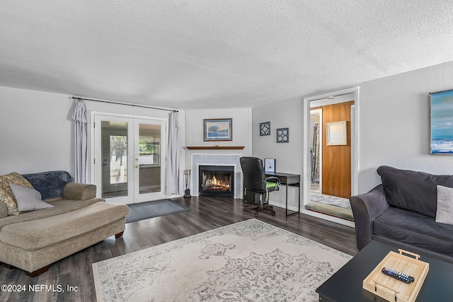 living room featuring a tile fireplace, a textured ceiling, dark hardwood / wood-style flooring, and french doors