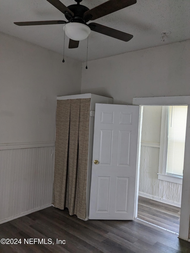 bonus room featuring ceiling fan, wood walls, and dark hardwood / wood-style flooring