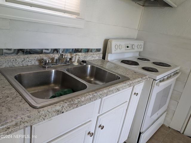 kitchen featuring white cabinets, tile patterned floors, white range with electric stovetop, and sink